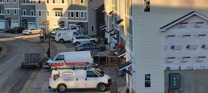 Construction site with various work vehicles parked near residential buildings