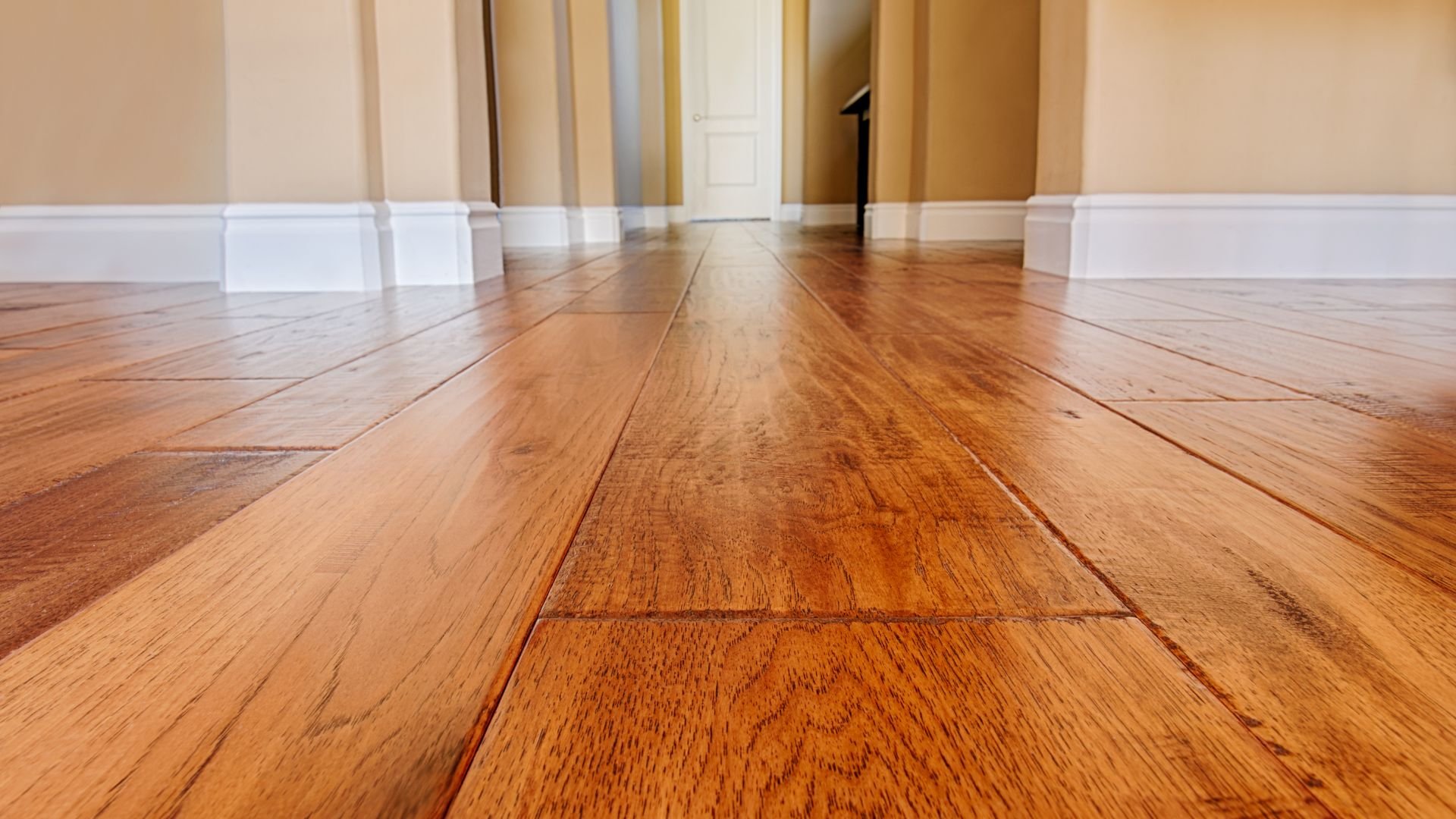 Polished hardwood floor with warm wood tones and white baseboards