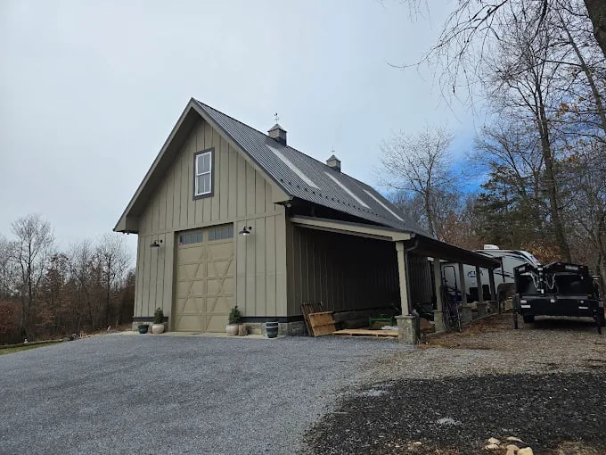 Rustic wooden barn-style garage with large door and attached carport