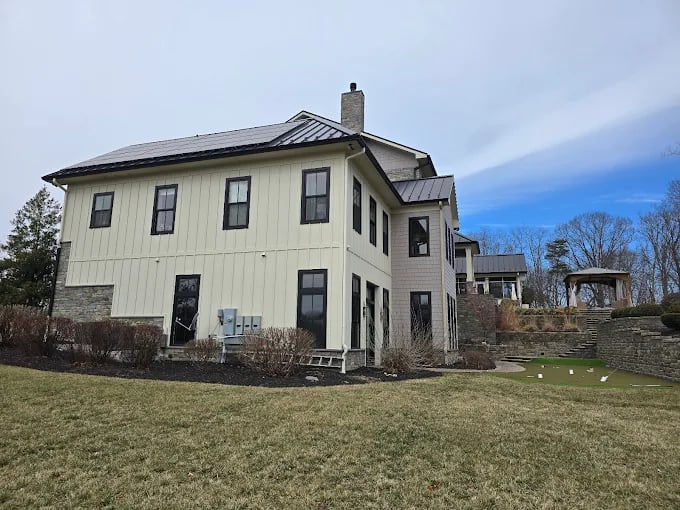 Modern farmhouse with stone accents and metal roof on grassy landscape