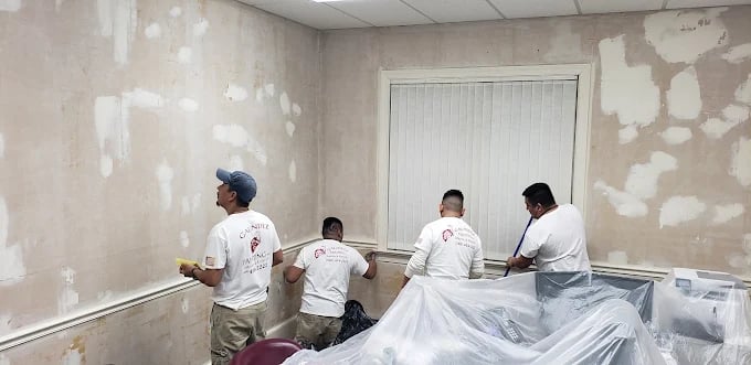 Workers preparing walls for painting with drop cloths and supplies
