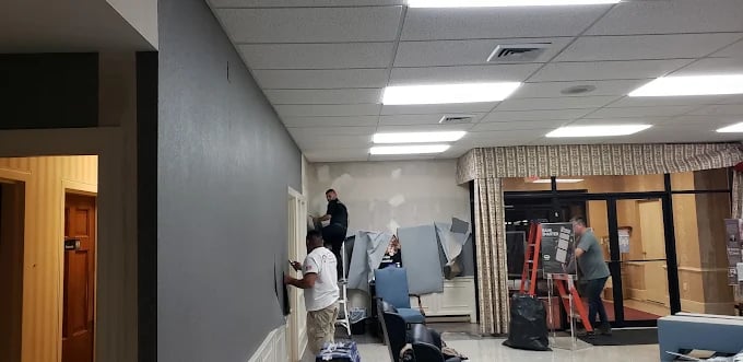 Workers renovating an office space with ladders and painting equipment