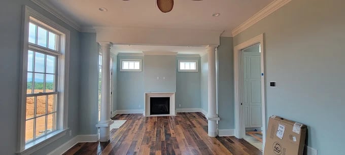 Empty room with wooden floors, fireplace, and blue-gray walls
